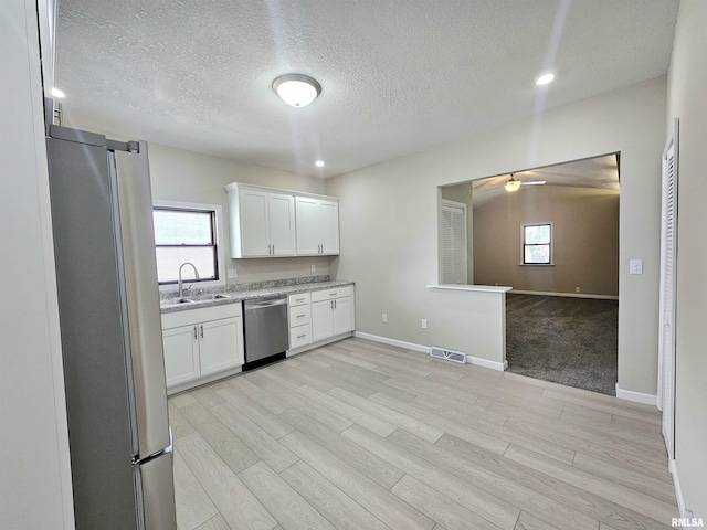 kitchen with a sink, stainless steel appliances, visible vents, ceiling fan, and white cabinetry