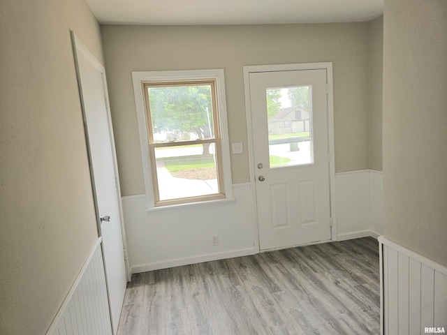 doorway to outside with wainscoting and light wood-style flooring