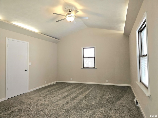 unfurnished room featuring visible vents, vaulted ceiling, ceiling fan, baseboards, and dark carpet
