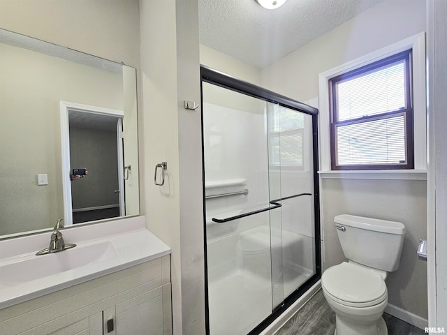 full bath with a textured ceiling, toilet, a shower stall, vanity, and wood finished floors