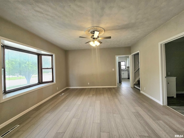 spare room with baseboards, visible vents, wood finished floors, and a ceiling fan