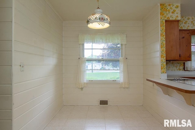 unfurnished dining area with light tile patterned floors and ornamental molding