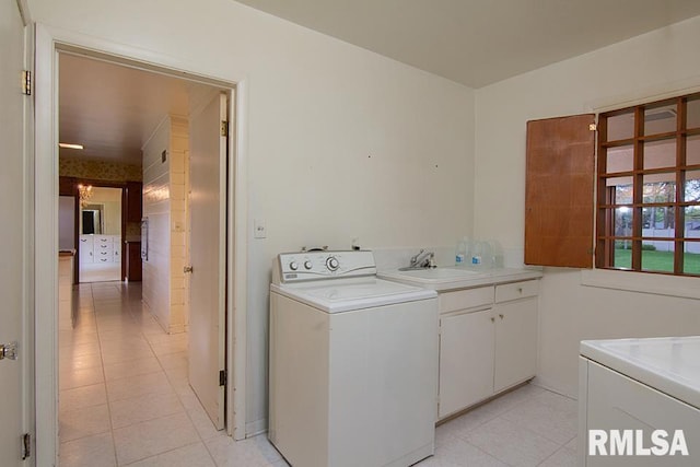 washroom with a sink, cabinet space, light tile patterned floors, and washer / dryer
