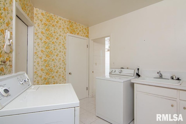 washroom with a sink, cabinet space, light tile patterned floors, washing machine and dryer, and wallpapered walls