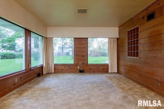 unfurnished sunroom featuring wooden walls, visible vents, and carpet