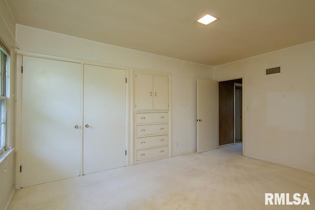 unfurnished bedroom featuring a closet, visible vents, and light colored carpet