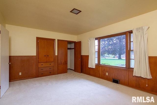 unfurnished bedroom with wainscoting, wooden walls, and visible vents
