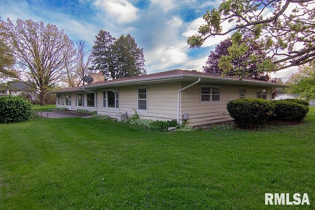 back of property with a yard, a patio, and a chimney