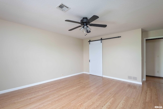 1360 Kimberly Ridge Rd Unit 309, Bettendorf, IA 52722 - unfurnished bedroom featuring light wood-type flooring, visible vents, a barn door, and baseboards