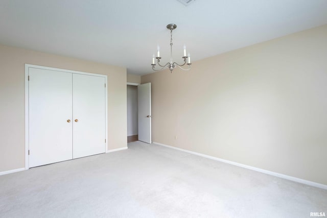 1360 Kimberly Ridge Rd Unit 309, Bettendorf, IA 52722 - unfurnished bedroom featuring a closet, light colored carpet, visible vents, an inviting chandelier, and baseboards