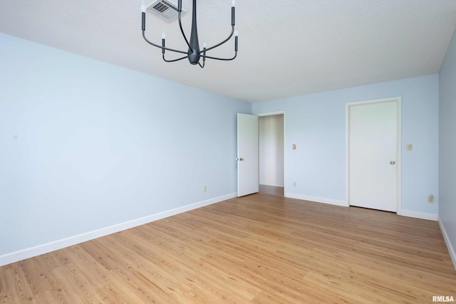 1360 Kimberly Ridge Rd Unit 309, Bettendorf, IA 52722 - spare room with light wood-style floors, a chandelier, baseboards, and visible vents