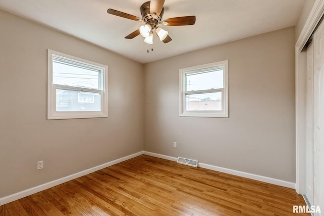 unfurnished room with light wood finished floors, visible vents, baseboards, and ceiling fan