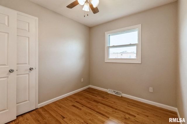 empty room featuring ceiling fan, light wood-style flooring, baseboards, and visible vents