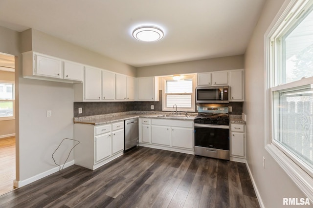 kitchen featuring dark wood finished floors, a sink, white cabinets, stainless steel appliances, and tasteful backsplash