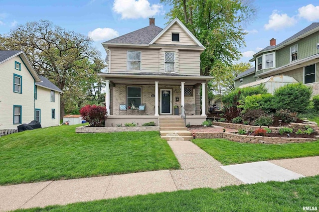 american foursquare style home with a porch, brick siding, a front lawn, and a chimney