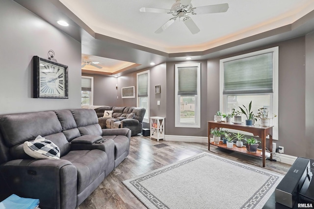living area with a tray ceiling, recessed lighting, baseboards, ceiling fan, and wood finished floors