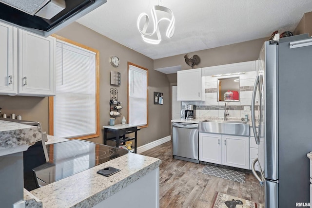 kitchen featuring white cabinets, light wood-type flooring, stainless steel appliances, and a sink