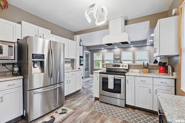 kitchen featuring stainless steel appliances, island exhaust hood, light wood finished floors, an inviting chandelier, and white cabinets