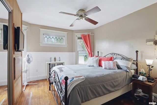 bedroom with light wood-style floors, baseboards, and ceiling fan