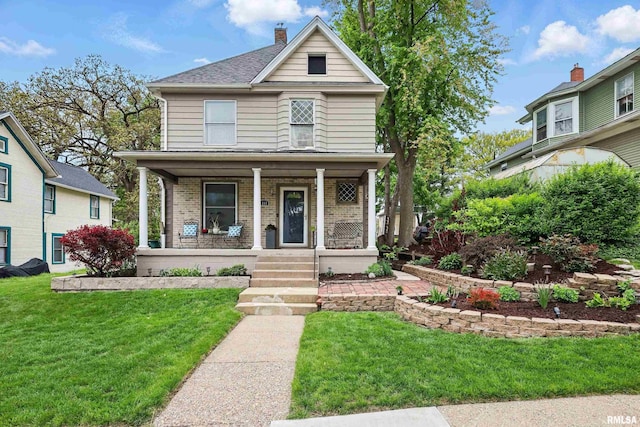 view of front of house featuring a porch, a front lawn, a chimney, and brick siding