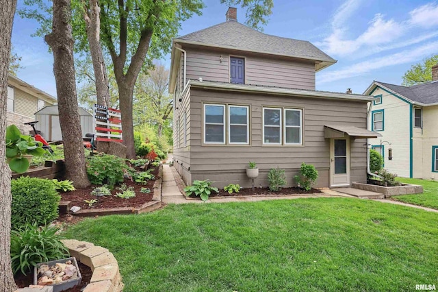 view of front of house with an outdoor structure, a chimney, a front yard, and a shed