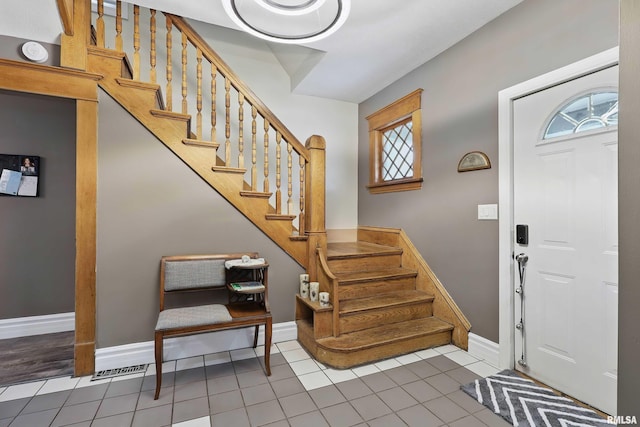 entryway with tile patterned floors, baseboards, and stairs