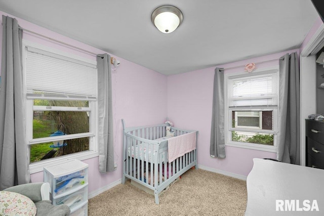 carpeted bedroom with baseboards and a crib