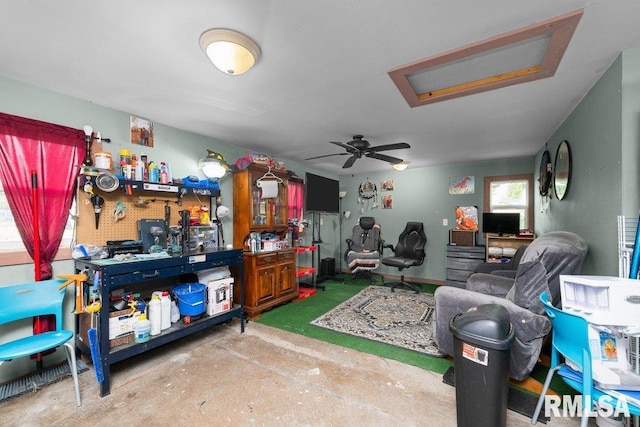 interior space with unfinished concrete flooring, attic access, and a ceiling fan