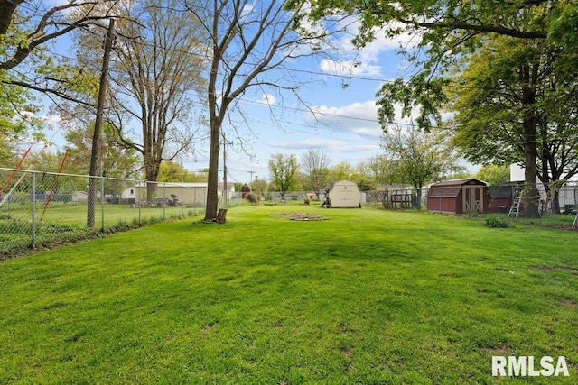 view of yard featuring an outbuilding, fence, and a storage unit