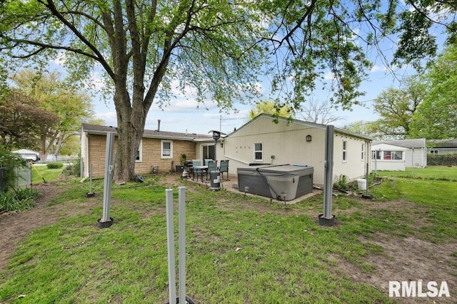 back of property featuring stone siding, fence, a lawn, a hot tub, and a patio area