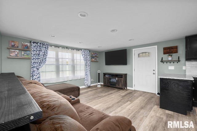 living area with baseboards, recessed lighting, and light wood-type flooring
