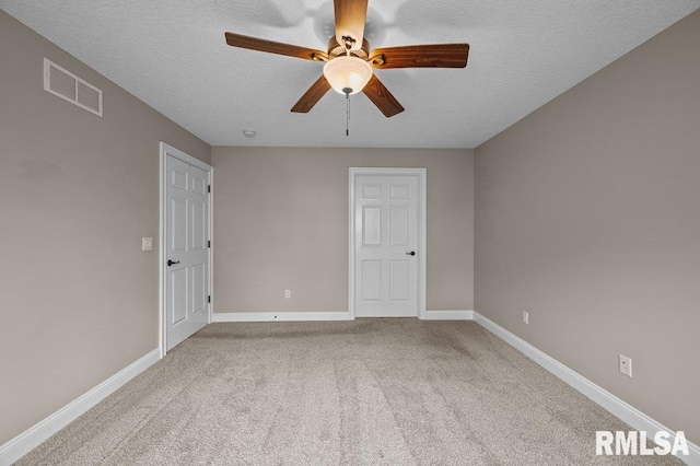 carpeted spare room featuring baseboards, ceiling fan, visible vents, and a textured ceiling