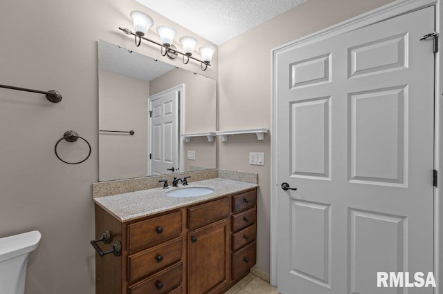 half bath with toilet, vanity, and a textured ceiling