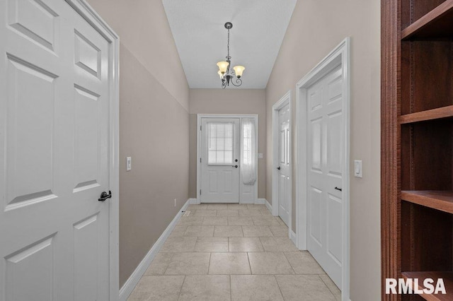 doorway to outside with an inviting chandelier, light tile patterned floors, baseboards, and lofted ceiling