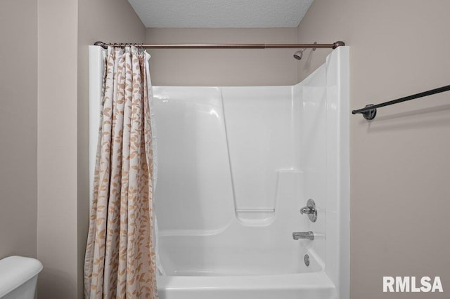 bathroom featuring shower / bath combo with shower curtain, toilet, and a textured ceiling