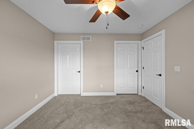 unfurnished bedroom featuring baseboards, a textured ceiling, visible vents, and carpet