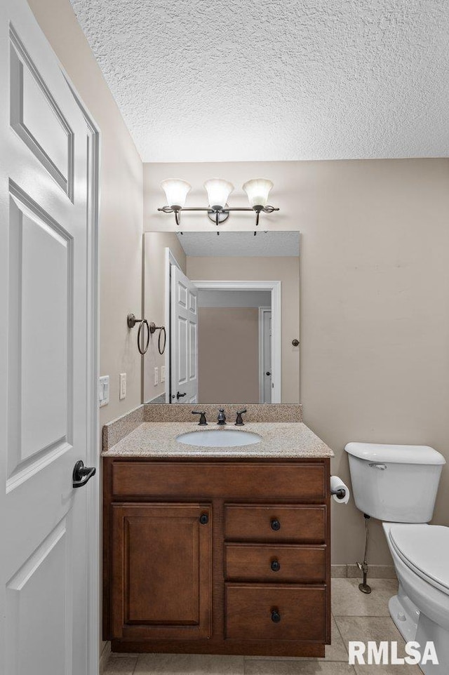 half bath with toilet, vanity, a textured ceiling, tile patterned floors, and baseboards