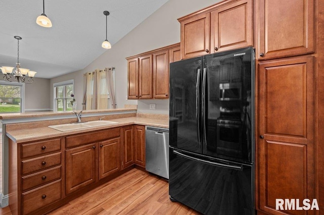 kitchen featuring freestanding refrigerator, lofted ceiling, stainless steel dishwasher, a sink, and a peninsula