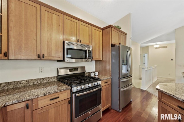 17 Blackstone Way, Le Claire, IA 52753 - kitchen with stainless steel appliances, vaulted ceiling, dark wood-style flooring, light stone counters, and brown cabinets