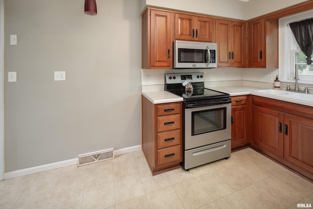 kitchen featuring brown cabinets, a sink, visible vents, light countertops, and appliances with stainless steel finishes