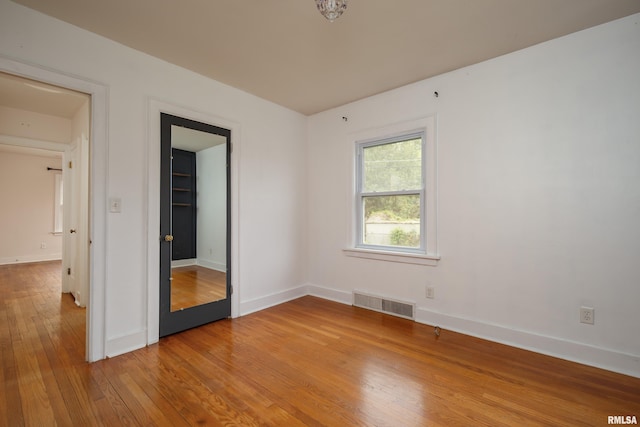 unfurnished room with light wood-style floors, visible vents, and baseboards
