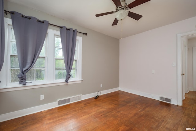 spare room featuring plenty of natural light, visible vents, and wood finished floors