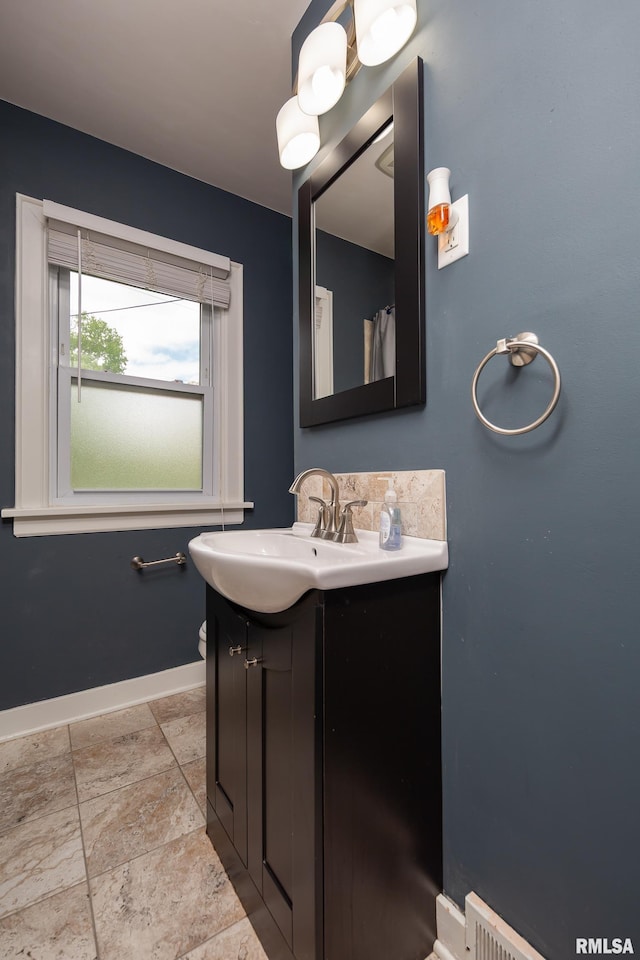 full bathroom with vanity, toilet, baseboards, and stone tile flooring