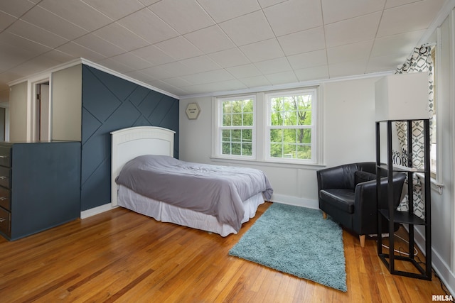 bedroom with baseboards, crown molding, and hardwood / wood-style flooring