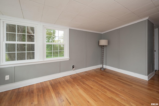 unfurnished room featuring baseboards, wood-type flooring, and crown molding