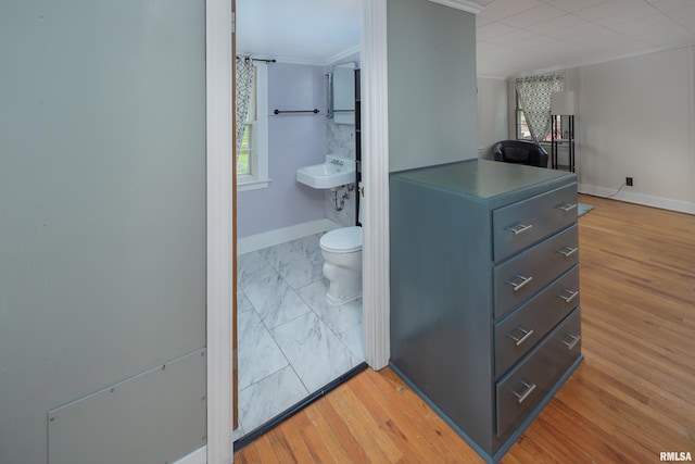 bathroom featuring baseboards, ornamental molding, toilet, and wood finished floors
