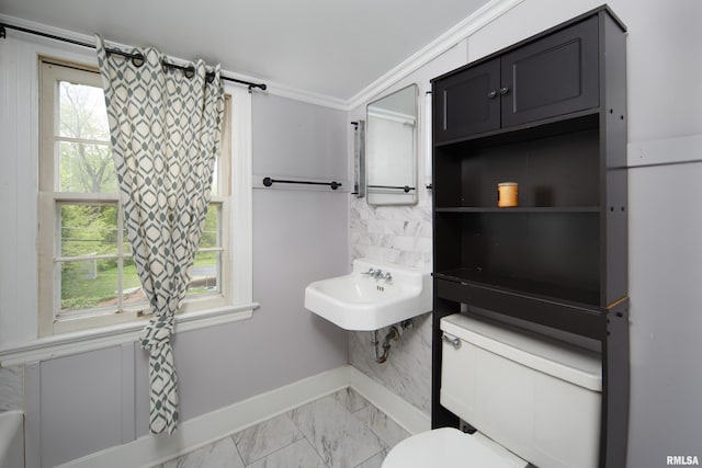 bathroom with marble finish floor, toilet, baseboards, and plenty of natural light