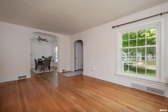 unfurnished room with plenty of natural light, arched walkways, and visible vents