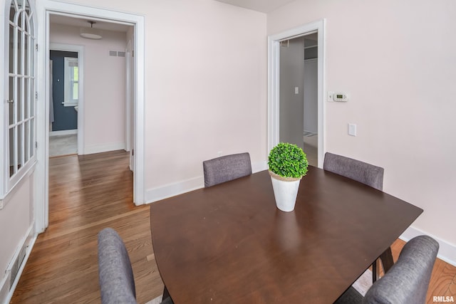 dining area with baseboards, visible vents, and wood finished floors