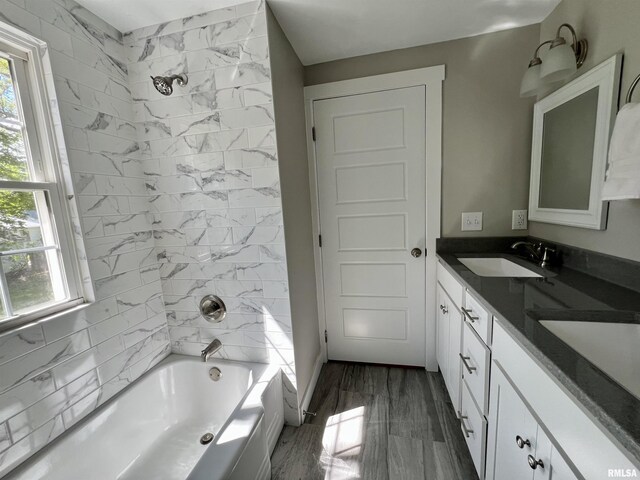 full bath with double vanity, washtub / shower combination, plenty of natural light, and a sink